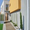 Porte d’entrée moderne TECK en aluminium plaxé bois poignée bâton de tirage pièce décorative en aluminium coloris RAL noir Finitions mat gamme PASSAGE sur une façade de maison moderne